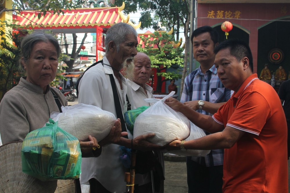 決勝村關聖帝廟理事長楊振明（右一）和副理事 長兼財政陳昶霖（右二）向窮人派發大米。