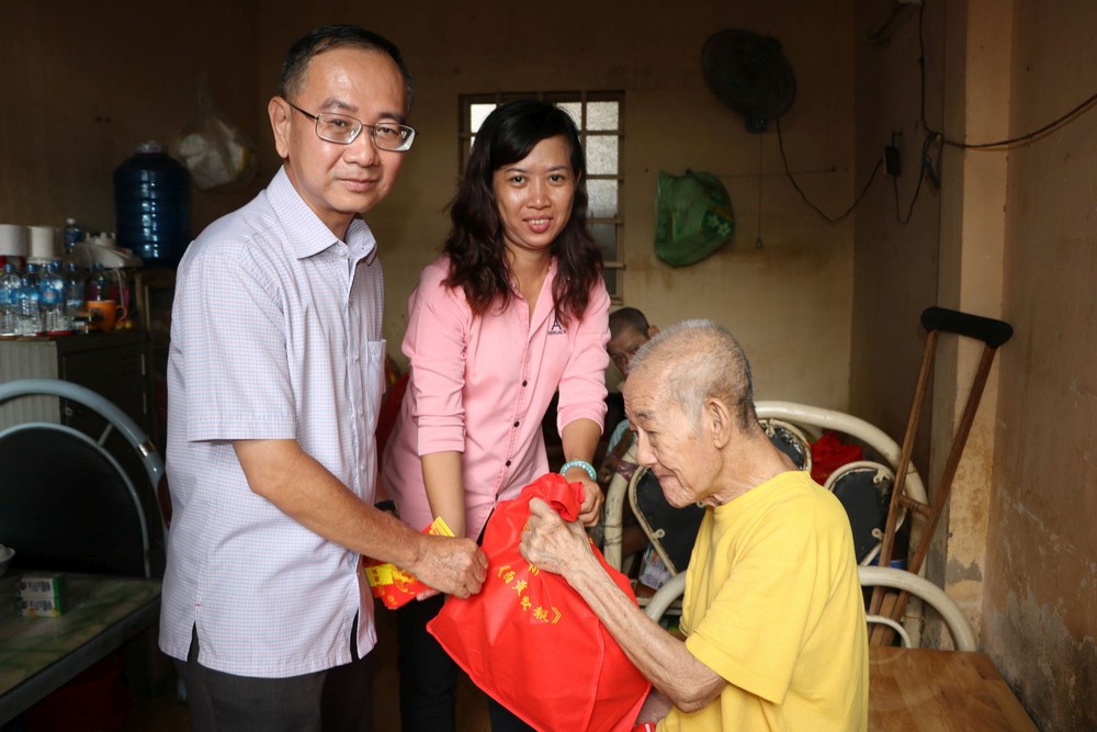 本報編委兼編輯部主任范興及工會副主席 陳月寶向玉光寺老人贈送禮物。