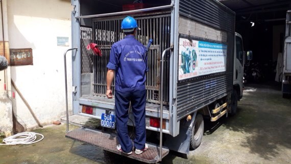 工作隊有專用車，車上有狗籠，車身兩邊有宣傳看板，工作人員身穿 背後印有市獸醫分局動物防疫和檢疫站字樣的深藍色制服。