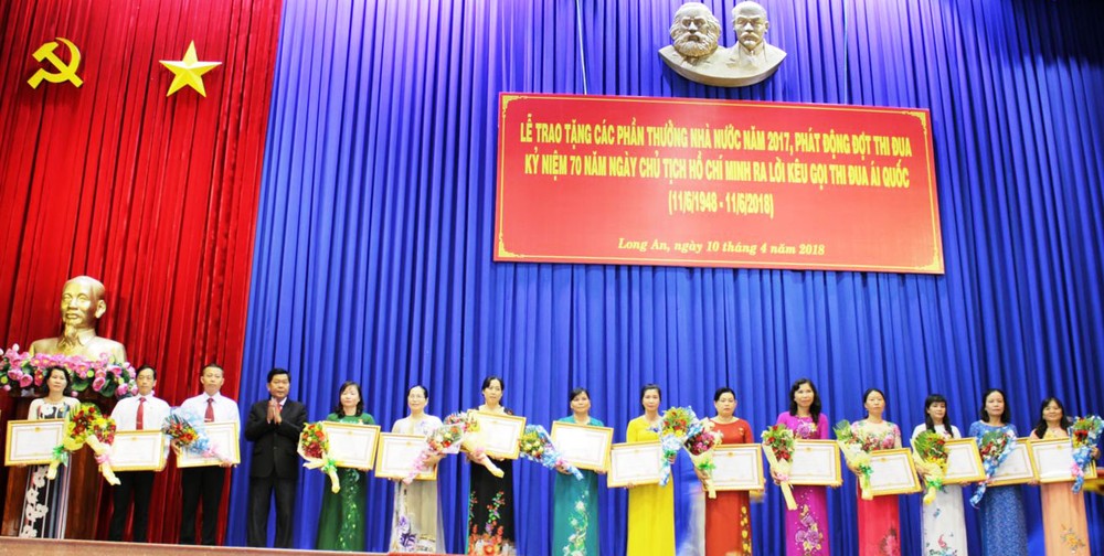 承蒙國家主席的委託，隆安省人委會主席陳文勤向達標的教師頒授“優秀教師”稱號。（圖源：隆安報）