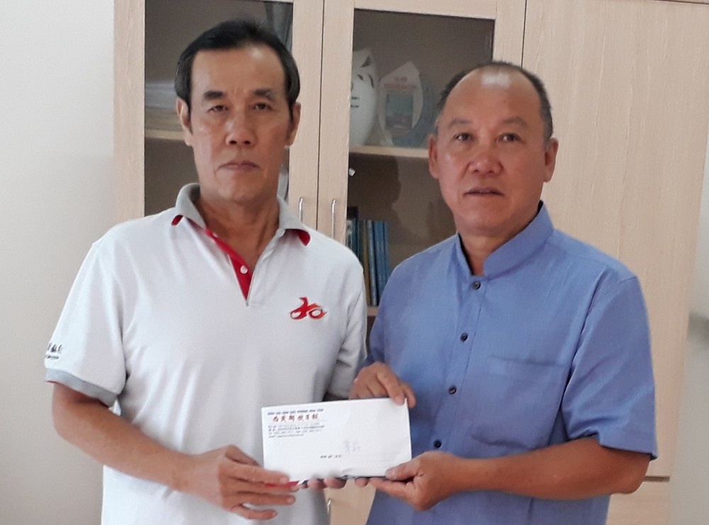 本報時事組組長兼讀者-社會慈善工作組負責人徐國樑(左)向芽莊華人會館會長、廣東會館會長、啟明華文學校重建委員會主席鄭成龍轉交讀者捐助的6040萬元。