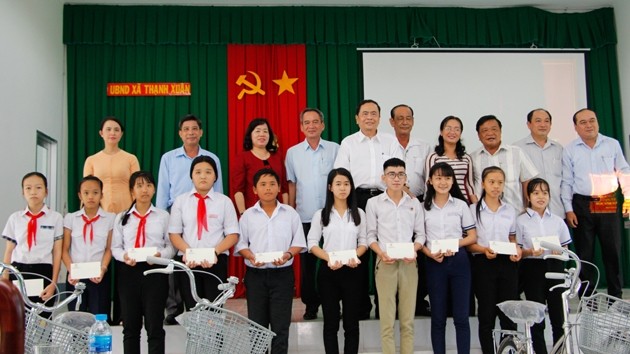 越南祖國陣線中央委員會主席陳清敏同志（後排左五）向貧窮好學子弟頒發助學金及自行車後同大家合影留念。（圖源：馮勇）