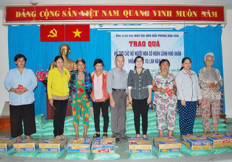 本報編委兼編輯部主任范興(右五)與新富 郡祖國陣線委員會副主席阮氏雪梅(右四)給貧 困戶贈送禮物。