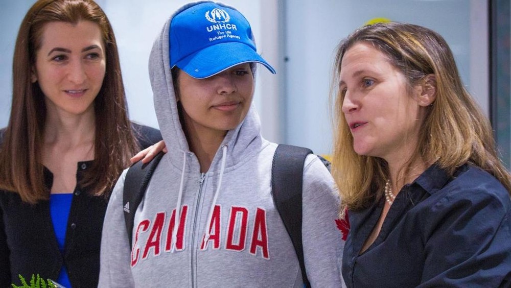 拉哈芙(中)身著寫有“加拿大”字樣的灰色運動帽衫、頭戴印有聯合國難民署標誌的棒球帽步出機場。（圖源：AFP）