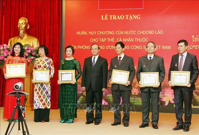 老撾新聞文化與旅遊部部長波顯坎‧馮達拉同志（中）頒發獎狀並合照。（圖源：越通社）