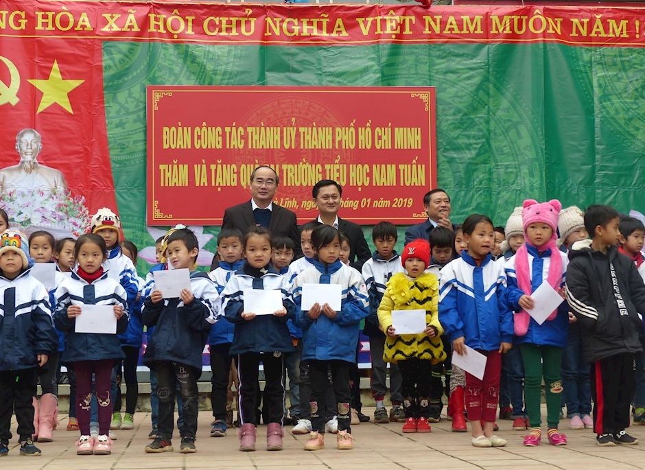 市委書記阮善仁（後排左一）探望南俊小學並向該校貧困小學生贈送禮物。（圖源：忠堅）