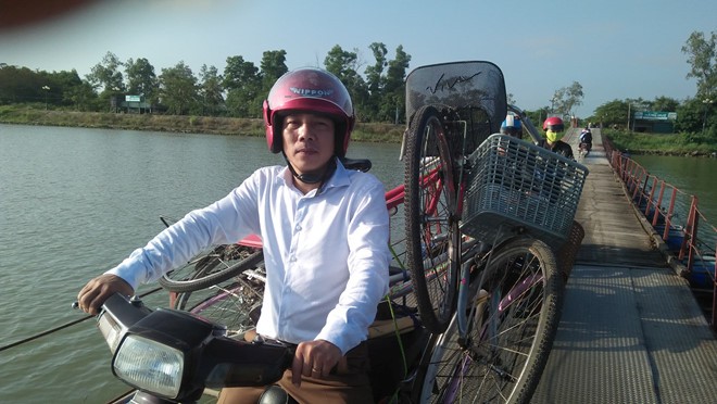 黃友喬老師用摩托車載自行車騎過廣治省趙峰縣趙度浮橋，以給該地學生們贈送車子。
