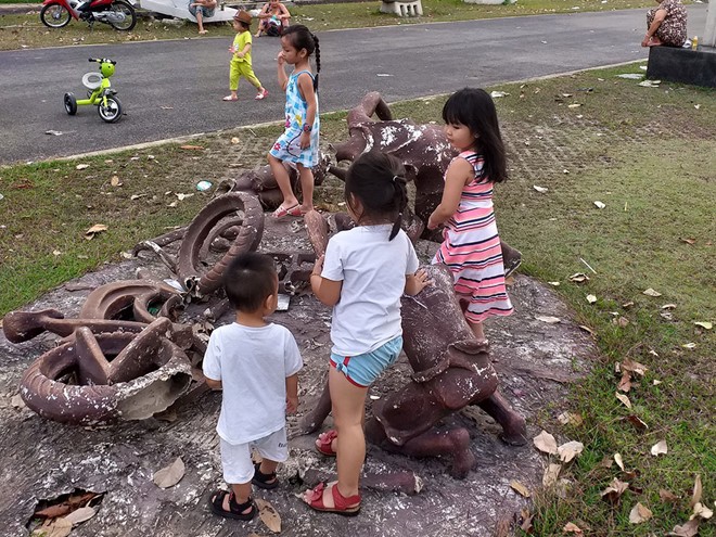 小孩們在一座壞塑像組合上玩耍。