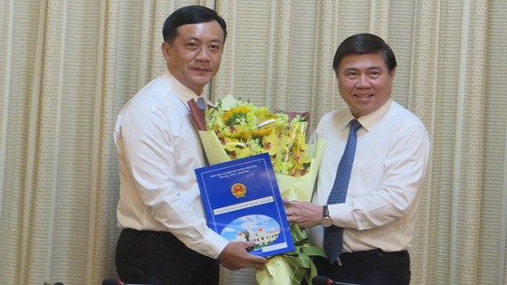 新任市人委會辦公廳主任何福勝（左）從市人委會主席阮成鋒手中接過人事委任《決定》和祝賀鮮花。（圖源：明蓉）