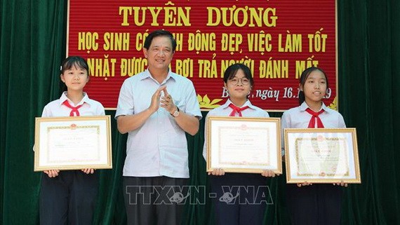 河內市教育與培訓廳副廳長范春進向三名拾遺不昧學生頒發獎狀。（圖源：越通社）