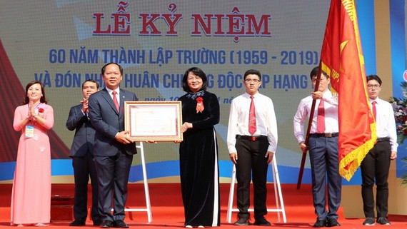 國家副主席鄧氏玉盛（中）向梁文悴高中專校頒授二等獨立勳章。（圖源：阮長）