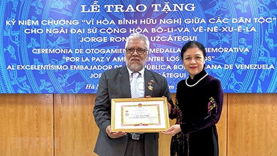 阮芳娥大使（右）代表VUFO領導向委內瑞拉共和國特命全權大使豪爾赫‧隆東‧烏斯卡特吉頒贈紀念章。（圖源：越通社）