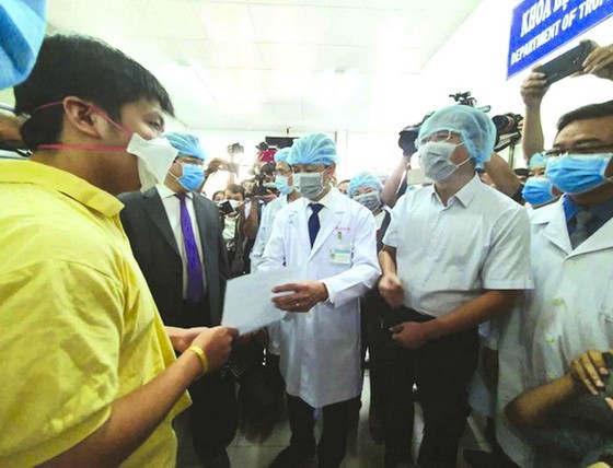 大水鑊醫院院長阮知識醫生向病人李子超(黃衣)遞交出院證。