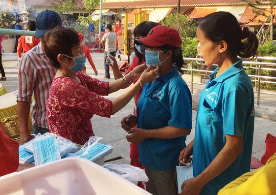 華人商販應氏蓮(左一)正在向消費者派發口罩。