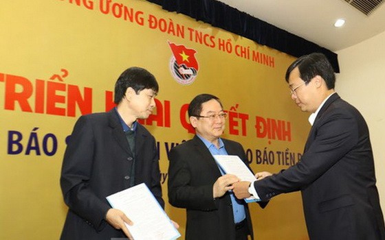 共青團中央書記處第一書記黎國鋒（右）向《前鋒報》總編輯黎春山頒發人事委任《決定》。（圖源：《前鋒報》）