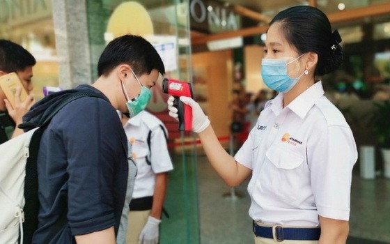 一個購物中心入口處，工作人員在檢查顧客的體溫。（圖源：互聯網）