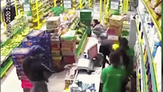 一名手持著疑似手槍的劫匪控制收銀櫃檯員被監控器錄取的畫面。（圖源：視頻截圖）