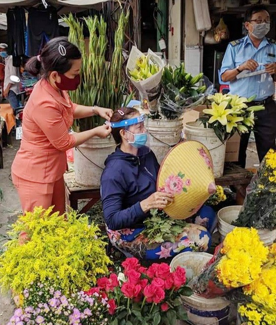 第五郡第十一坊婦女會主席 親自向商販戴上防護面罩。