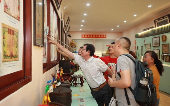 作者的叔父在“西堤華人懷舊物品展”上向觀眾介紹我家昔日的“全家福”。