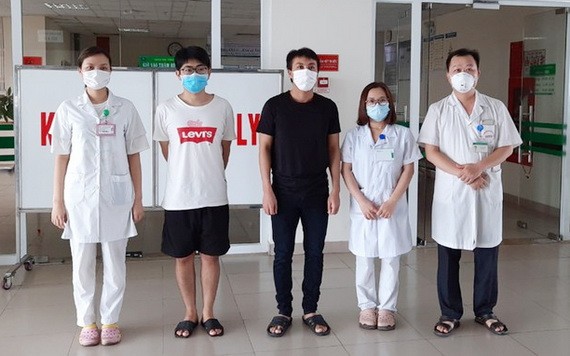 兩名新冠肺炎患者（左二、三）病癒出院前同醫護人員合照。（圖源：VOV）