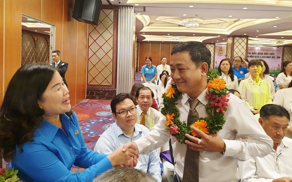 第五郡勞動聯團主席黎氏碧幸（左一）向模範勞工戴上花環祝賀。