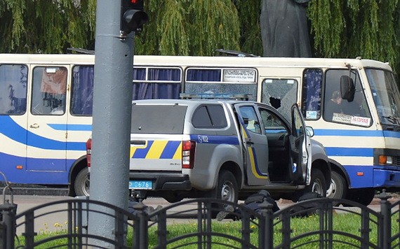 烏克蘭一輛公交車於7月21日在盧茨克市被一名武裝人員劫持，三名執法人員臥倒在公交車旁邊的一輛汽車後面的地上，與歹徒對峙。（圖源：路透社）