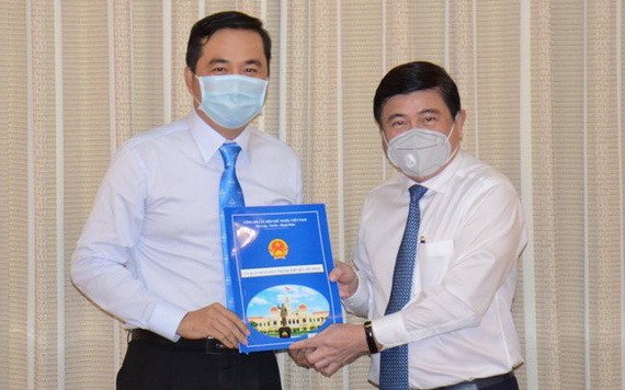 新任市工商廳長裴佐黃宇（左）從市人委會主席阮成鋒手中接過人事委任《決定》。（圖源：芳陲）