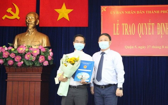 新任第五郡人委會副主席阮春忠（左）接領人事委任《決定》時與市人委會副主席楊英德合照。（圖源：梅花）