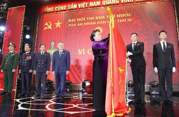 國會主席阮氏金銀為人民法院傳統旗幟上佩掛一等獨立勳章。（圖源：越通社）