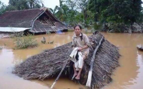 在一片汪洋的洪水之中，一名婦女坐在草屋頂上等待營救。（圖源：互聯網）