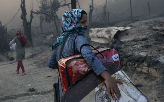 9月9日，希臘萊斯博斯島的莫里亞難民營發生大火後，一位移民帶著自己的物品離開難民營。（圖源：路透社）