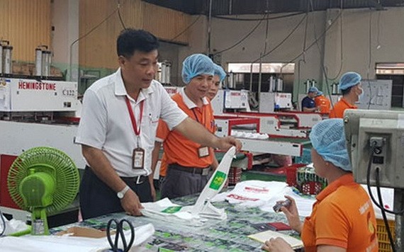 南泰山公司黨支部書記阮梅雄（左）與同事們討論產品質量。