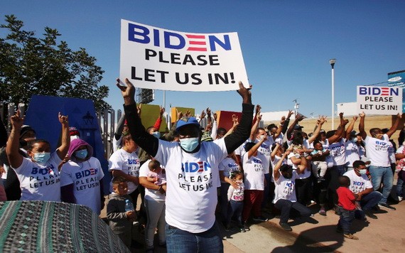 來自中美洲和其他民族的移民在美墨邊境附近聚集並高舉標語，籲拜登讓他們進入美國。（圖源：路透社）
