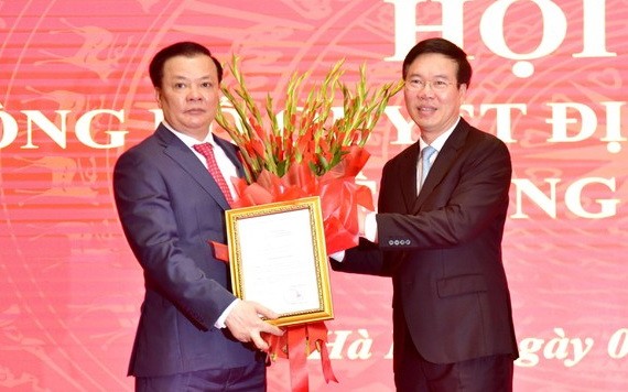新任河內市市委書記丁進勇（左）從黨中央書記處常務書記武文賞手中接過人事委任《決定》和祝賀鮮花。（圖源：VGP）