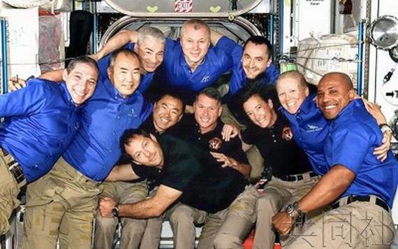 新到站的 4 名宇航員（黑衣者）同空間站內的宇航員們一起合影。（圖源：共同社）