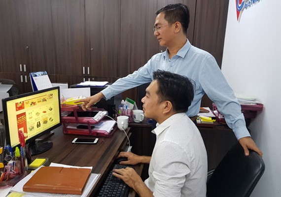 陳輝強（站）與同事一起查看在“堤岸線上集市”上商品。