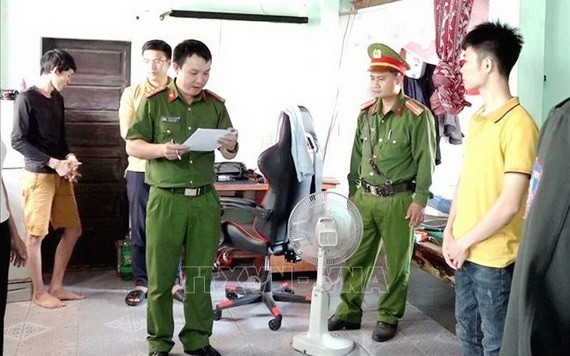 涉賭嫌犯（黃衣）在聽取執法警員宣讀逮捕令。（圖源：越通社）