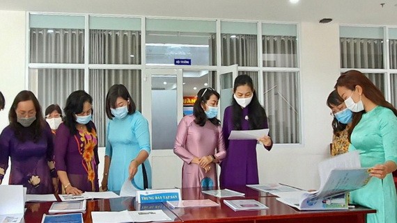 市婦聯會副主席林氏玉華（右三）、郡婦聯會主席梁菁竹在閱讀“推崇學習胡志明思想、道德與榜樣的集體與個人”特刊。