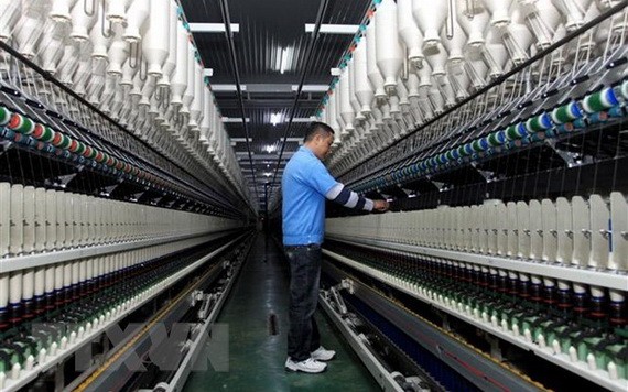 一名工人在一家紗線車間操控生產線。（圖源：越通社）