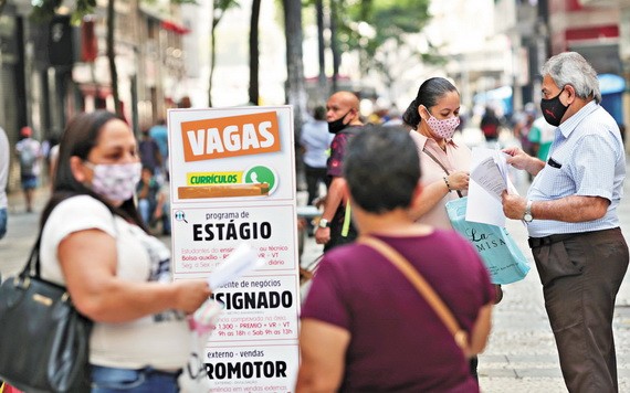 受疫情影響，全球失業率暴增。圖為巴西民眾查看職位列表公告板，一名女性將簡歷交給了招聘機構工作人員。（圖源：路透社）