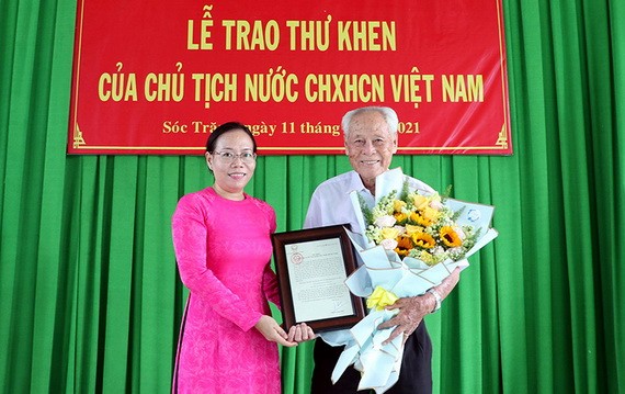 受國家主席的委託，滀臻省人委會副主席黃氏艷玉（左）向陳剛老人家轉交表彰函。