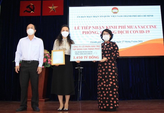 本市市委副書記阮胡海（左）與市越南祖國陣線委員會主席蘇氏碧珠（右）接受萬盛發集團捐助購買疫苗的一萬四千五百億元善款。