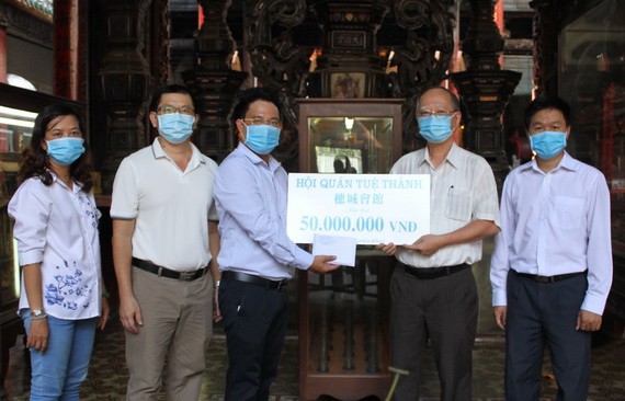 穗城會館理事長盧耀南(右二)和副理事長陳志豪(右一)向本報領導移交5000萬元贈款。