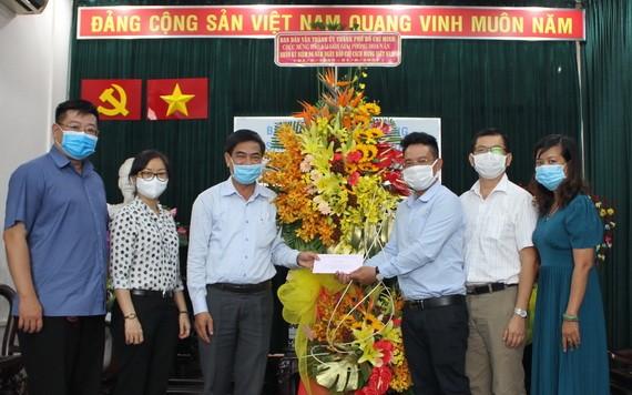 市委民運處副主任吳文倫(左三)向本報編委文忠孝(右三)贈送鮮花。