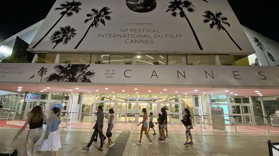 人們走過法國嘎納電影宮外的電影節海報。（圖源：互聯網）