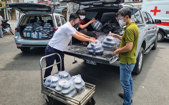 阮維述(左)正在把飯菜搬上車以載到醫院送給病童。