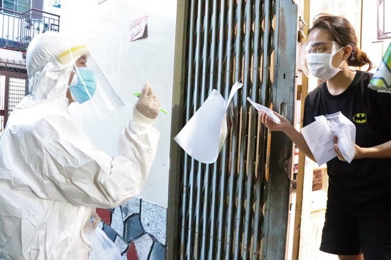 軍醫學院戰士挨家挨戶派發新冠病毒快速檢測試劑盒並指引民眾使用。