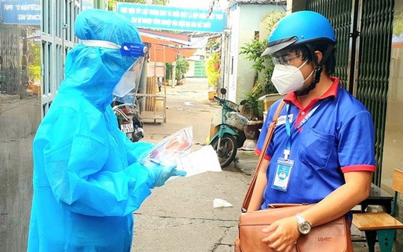 市共青團幹部周進祿（右）與醫護人員討論關於新冠患者居家治療的情況。