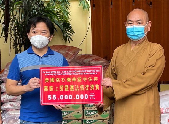 麒麟（左）代表旅美僑胞向釋慧功法師（右）捐贈善款。