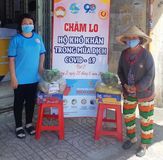 第十一郡第二坊婦女會主席林玉明（左）將民生必需品交給貧困者。